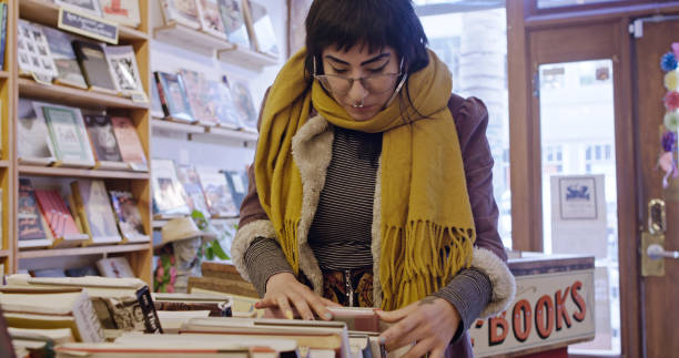 istock Woman Looking through Box in Used Bookstore 1297456361