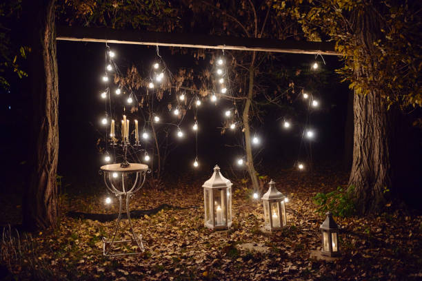 istock Night wedding ceremony with candles, lanterns and bulb lights on tree outdoors, copy space 1297460185