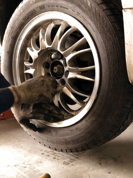 Auto mechanic man with electric screwdriver changing tire outside. Car service. Tire installation concept. Replacement of winter and summer tires. Hands replace tires on wheels. mecánico automático con destornillador eléctrico cambiando neumático en el exterior. servicio de coche. concepto de instalación de neumáticos. reemplazo de neumáticos de invierno y verano. las manos reemplazan los neumáticos sobre las ruedas.