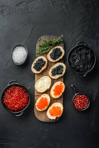istock Bruschettes with butter red and black caviar, on black background, top view flat lay 1297462038