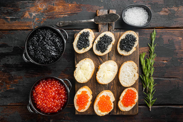 bruschette con caviale rosso burro e nero, su vecchio sfondo tavolo in legno scuro, vista dall'alto piatta laici - caviar salmon red gourmet foto e immagini stock