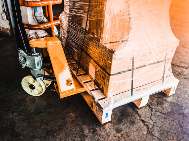 Worker driving forklift loading shipment carton boxes goods on wooden pallet at loading dock from container truck to warehouse cargo storage in freight logistics, transportation industrial, delivery trabajador conduciendo carretilla elevadora de carga cajas de cartón de mercancías en palet de madera en el muelle de carga desde el camión contenedor hasta el almacenamiento de carga de almacén en logística de carga, transporte industrial, entrega