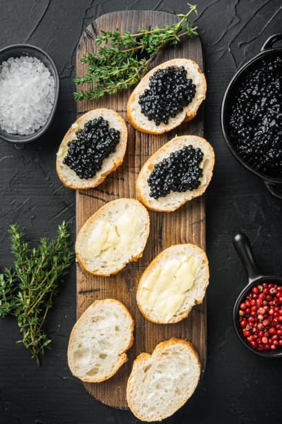 istock Black caviar served on baguette, on black background, top view flat lay 1297463726