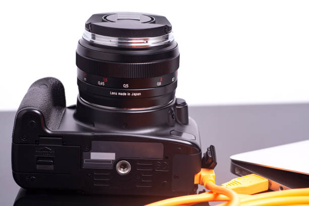 istock Digital photo camera connected to laptop with USB orange rolled cable 1297464452