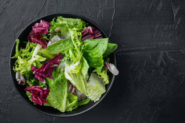 istock Bowls with mixed shredded salad lettuce leaves, on black background, top view flat lay  with copy space for text 1297464979