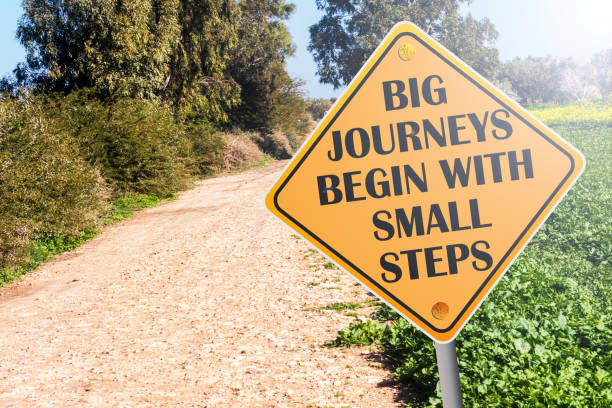 大きな旅は、道路上の小さなステップの看板で始まります - steps ストックフォトと画像