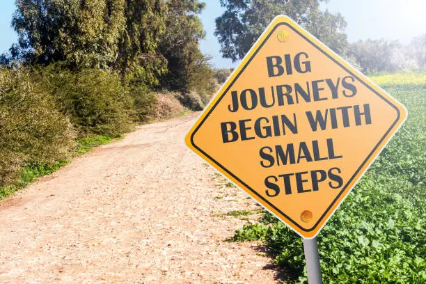 Big Journeys Begin With Small Steps sign on road