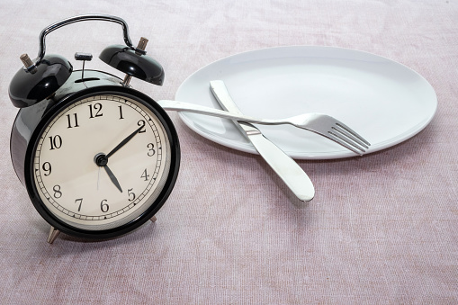 Weight loss or dieting concept of an alarm clock on a dinner plate
