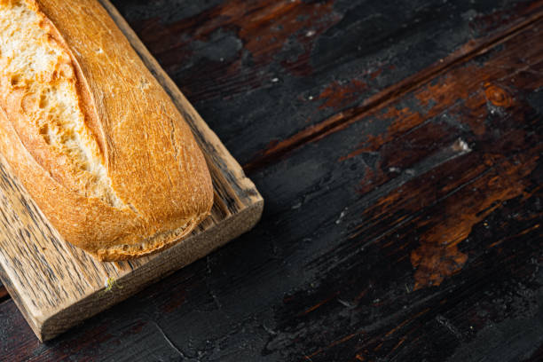 istock Freshly baked baguette, on old dark  wooden table background  with copy space for text 1297469437