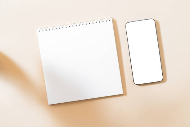 istock Flat Lay mockup of smartphone with blank screen, white notepad and contrasting shadows on color background 1297470402