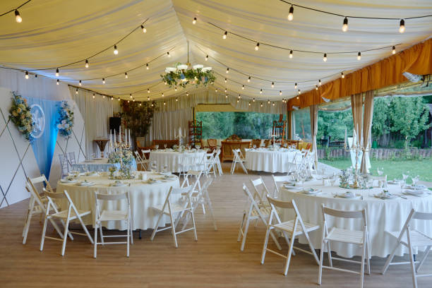 istock Table setting with sparkling wineglasses and cutlery on table, copy space. Place setting at luxury wedding reception. Round table and white wood chairs served for wedding banquet in restaurant 1297470448