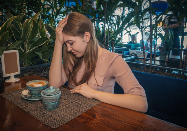 Heartbroken young lady is sitting in cafe and thinking regretfully. depressive lady drinks coffe in cafeteria.