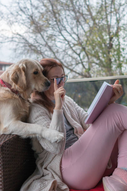 istock Woman reading book with her dog at balcony. 1297473807