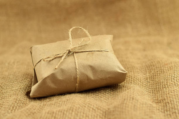 istock Simple eco friendly gift box package wrap with brown paper. Burlap background. Delivery of ecological products, eco-friendly packaging, craft. Green present concept, copy space. 1297474168
