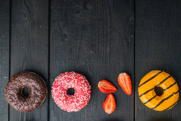 istock Glazed donuts, on black wooden table background, top view flat lay with copy space for text 1297474846