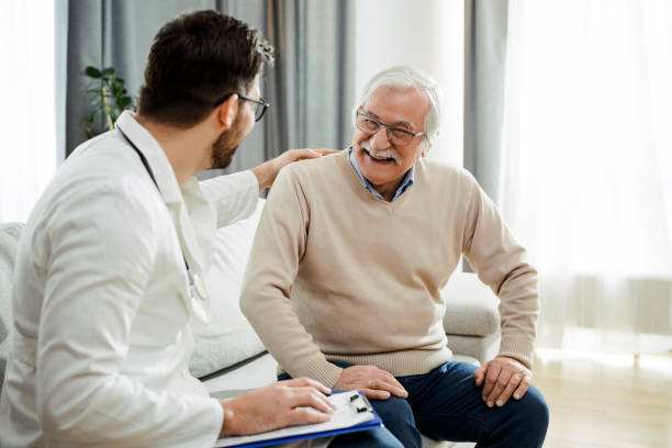 Young doctor on a house call Young doctor and senior man having a conversation sitting on a sofa doctor patient stock pictures, royalty-free photos & images