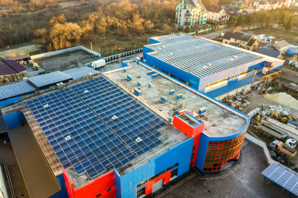 工業用建物の屋根に取り付けられた多くの光のボルタ電池パネルの航空写真。 - voltaic ストックフォトと画像