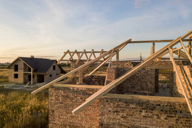 istock Private residential house with wooden roof frame structure under construction. Unfinished brick building under development. 1297475674