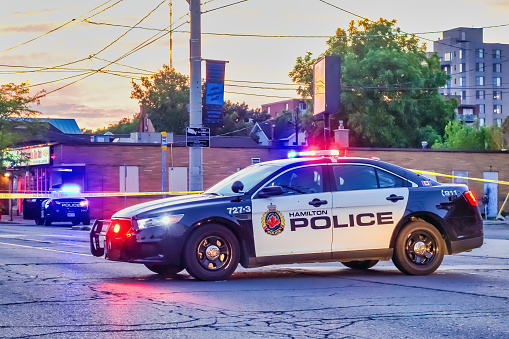 A police car stands at a roadblock in Hamilton, Ontario, Canada in the evening.