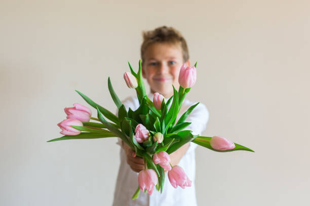 istock Young boy, kid child hands with pink tulips, flowers 1297479737