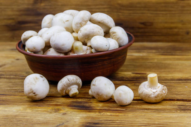 istock Fresh champignon mushrooms in ceramic bowl on the wooden table 1297480889