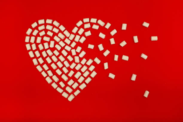 istock White marshmallow laid out of heart shape on red background. 1297481181