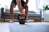 Closeup of man grabing kettlebell during home workout exercises