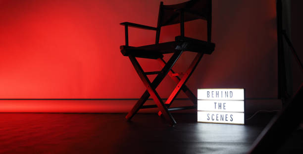 istock Behind the scenes letterboard text on Lightbox or Cinema Light box. Movie clapperboard megaphone and director chair beside. Background LED color change loop. static camera in video production studio. 1297482697