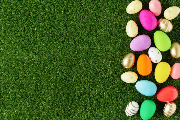 Colorful Easter eggs on grass background top view. Easter holiday greeting card.