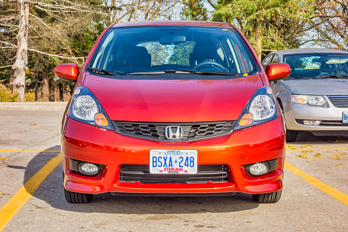 A Honda Fit small car is parked in a parking lot in Hamilton, Ontario, Canada on a sunny day.