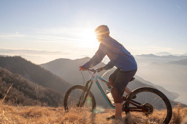 istock Female mountain biker rides along mountain ridge at sunrise 1297484879