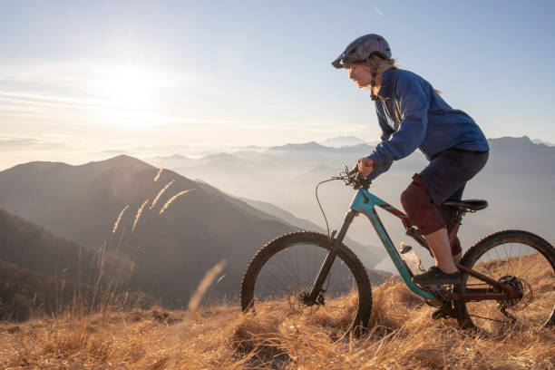 istock Female mountain biker rides along mountain ridge at sunrise 1297484884