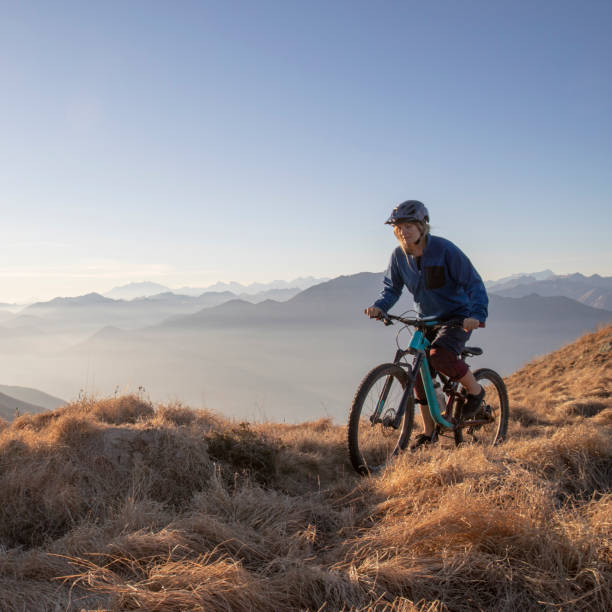 istock Female mountain biker rides along mountain ridge at sunrise 1297484903