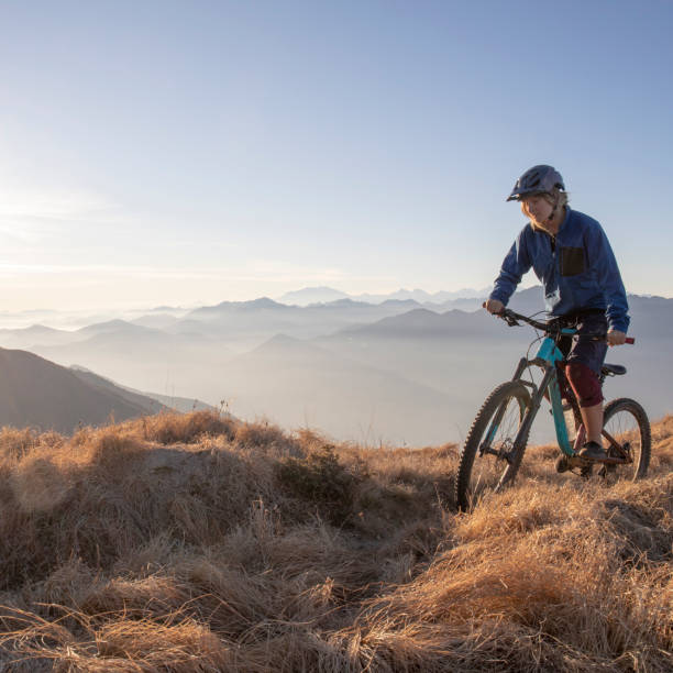 istock Female mountain biker rides along mountain ridge at sunrise 1297484912