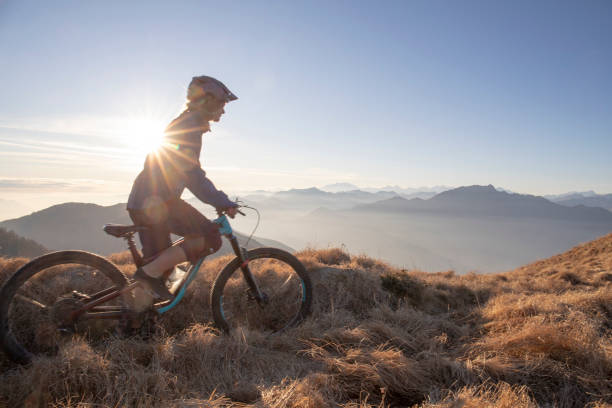 istock Female mountain biker rides along mountain ridge at sunrise 1297484959