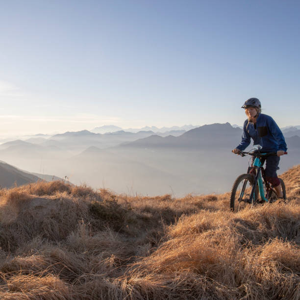 istock Female mountain biker rides along mountain ridge at sunrise 1297484974