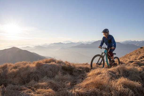 istock Female mountain biker rides along mountain ridge at sunrise 1297484984