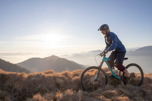 istock Female mountain biker rides along mountain ridge at sunrise 1297485005