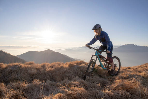 istock Female mountain biker rides along mountain ridge at sunrise 1297485089