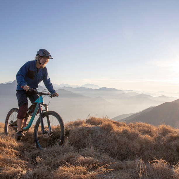 istock Female mountain biker rides along mountain ridge at sunrise 1297485194