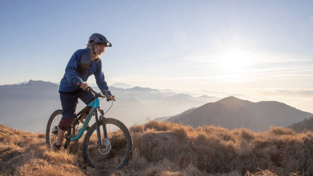 istock Female mountain biker rides along mountain ridge at sunrise 1297485233
