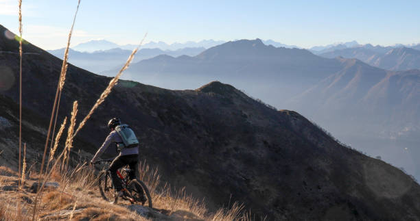 istock Mountain biker rides along grassy mountain ridge at sunrise 1297485253