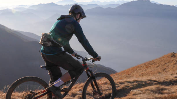istock Mountain biker rides along grassy mountain ridge at sunrise 1297485272