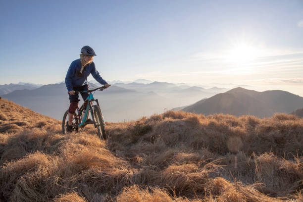 istock Female mountain biker rides along mountain ridge at sunrise 1297485310