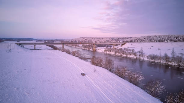 istock Bridge over the Dnieper River, snowy forest on a beautiful winter day with blue sky and clouds. Beautiful winter landscape with car along the river 1297486882