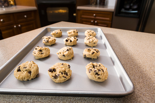 Individual balls of chocolate chip cookie dough on a tray ready to go into the oven.