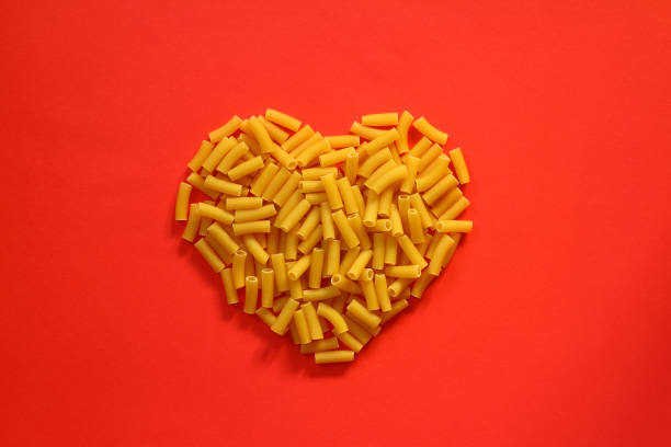 Pasta in the shape of a heart on a red background.