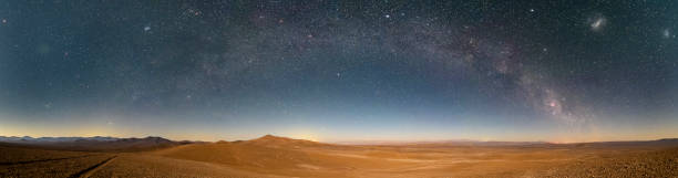 Photo of An amazing panoramic view of the Milky Way above Atacama Desert vast sand fields. An awe night sky view with our galaxy arm creating an arch in between the stars. An idyllic and motivational scenery.