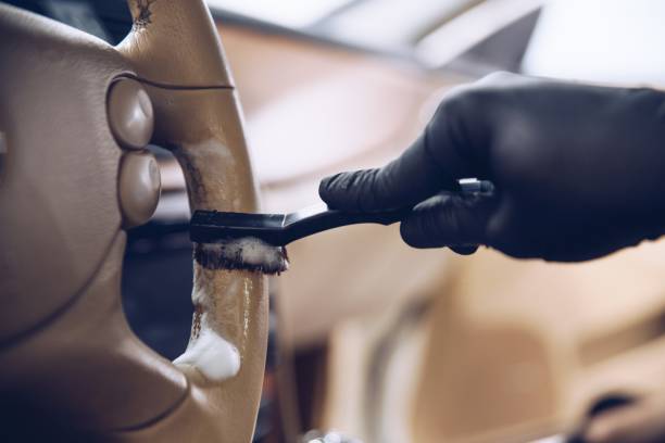 istock Car wash worker cleaning leather steering wheel with a brush. 1297491620