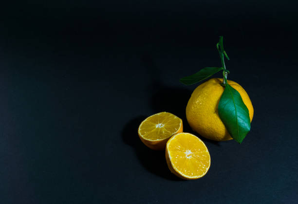 istock Tangerine cut with a green leaf on a black background 1297492555